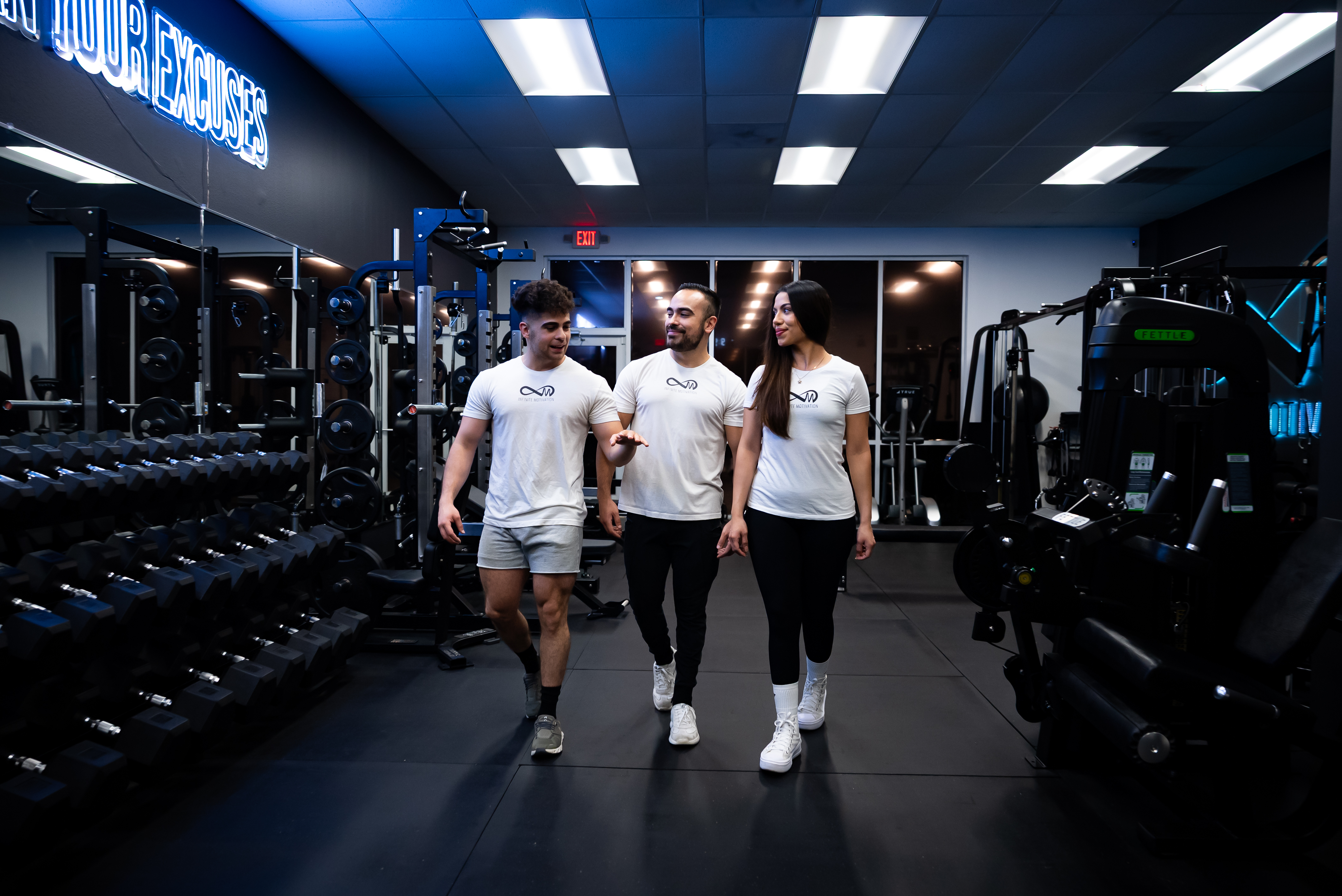 Team walking toward camera smiling in studio with dumbbell background