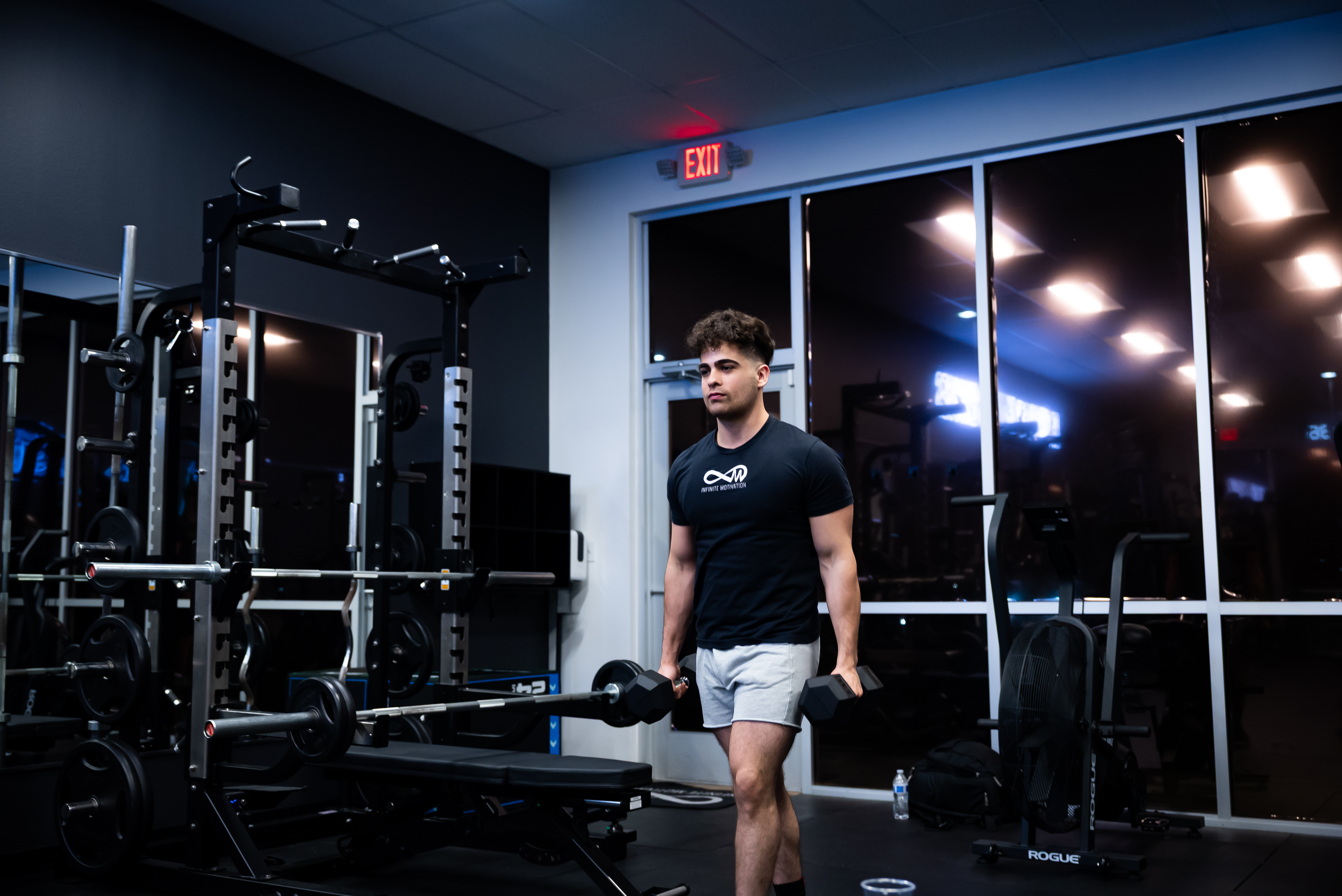 Trainer performing farmers walk with dumbbells demonstrating proper form